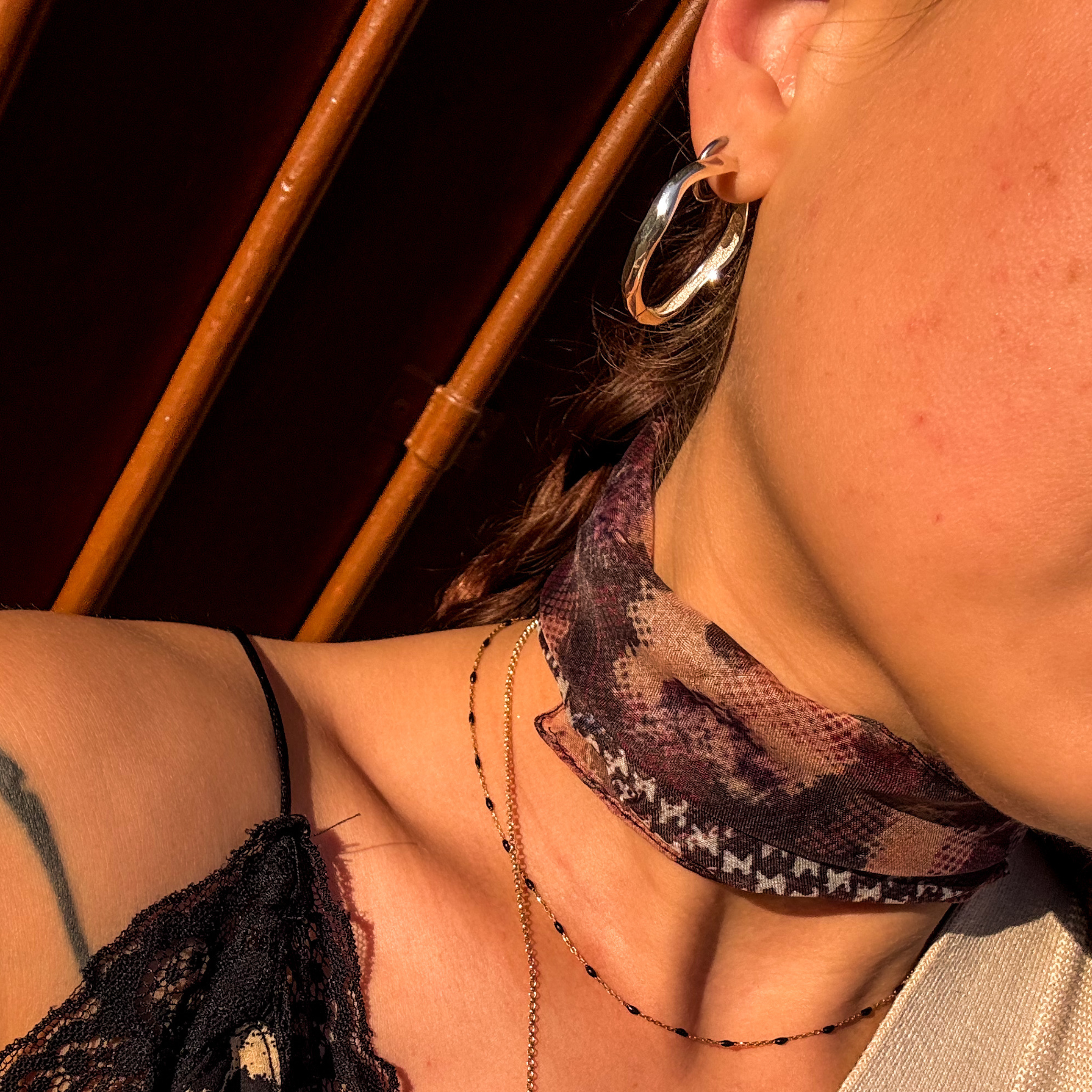 Close-up of a woman wearing silver Nesoi hoop earrings in warm light